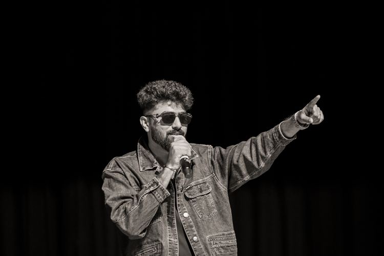 A black and white shot of a man on a mic pointing to the crowd