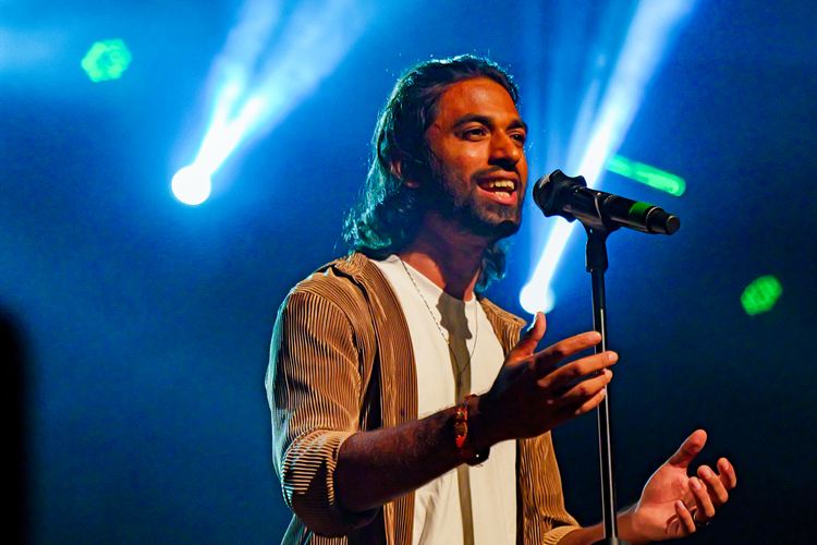 A singer on stage under blue spotlights