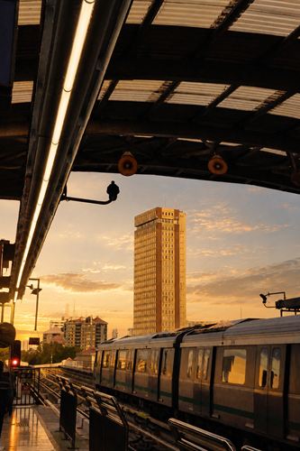 A metro platform at sunset with a tower block beyond the tracks